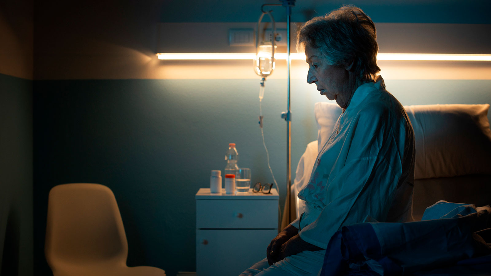 Vanhus istuu sängyllään sairaalassa yöllä. Kuva: Mostphotos.