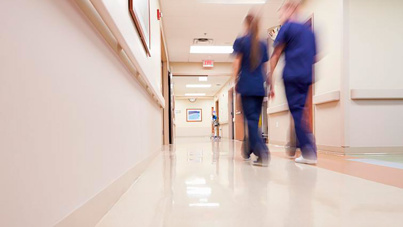 Kaksi hoitajaa kävelee kiireisesti sairaalan käytävällä.