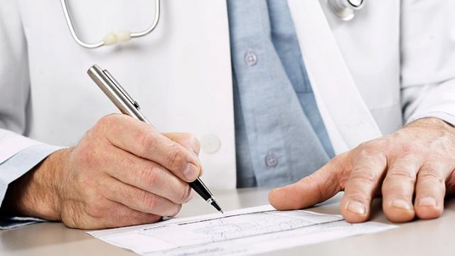 Lääkärin kädet kirjoittamassa paperiin