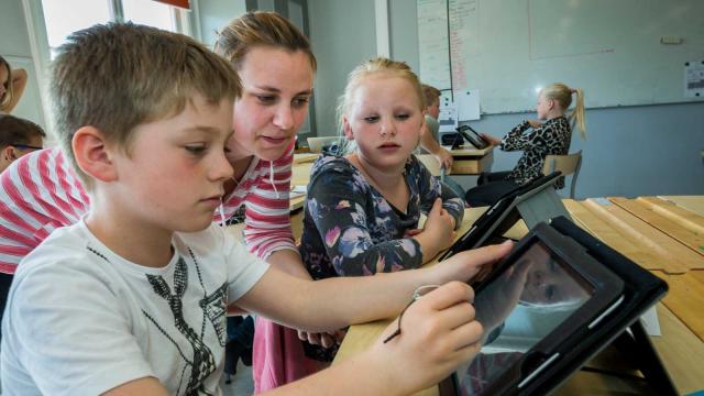 Lapset käyttävät iPadia oppitunnilla koulussa. Michael Folmer & Mostphotos
