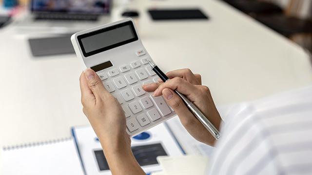 Henkilö tekee laskelmia laskimella. Kuva: Freepik.