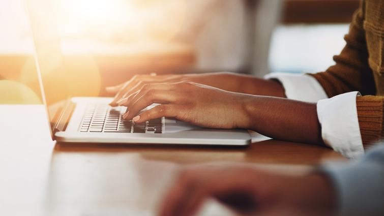 Henkilö kirjoittaa läppärillä.