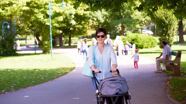 Äiti työntää lasta rattaissa puistossa. Kuva: Pixhill.