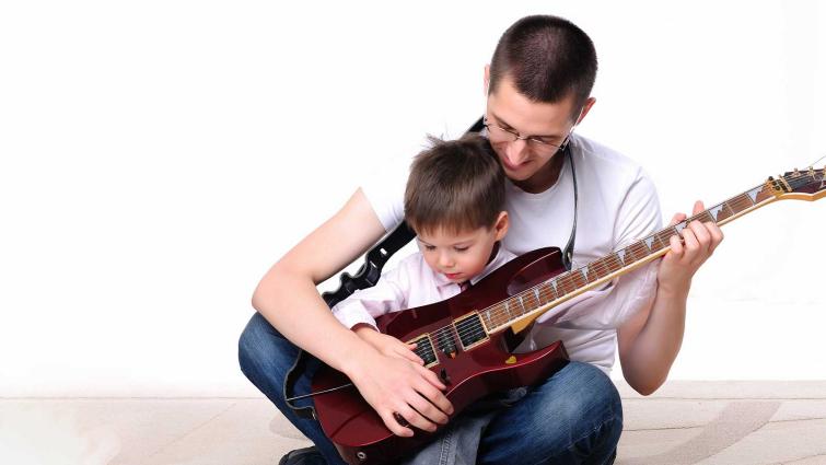 Isä ja poika harjoittelevat kitaran soittoa. Kuva: Pixhill.