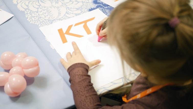 lapsi piirtää KT:n logo paperille