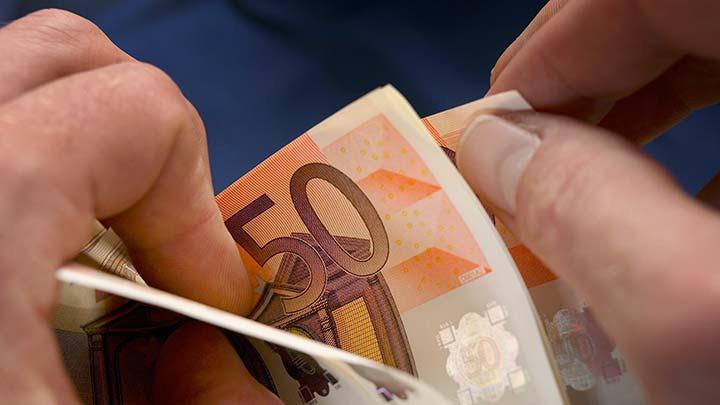 Kädet ja viidenkymmenen euron seteleitä